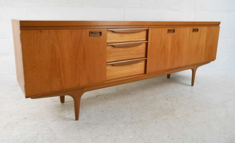 Long, stylish Mid-Century Modern sideboard in teak. Well designed with Classic Danish details, this unit features three drawers and three storage compartments. Please confirm item location (NY or NJ) with dealer.