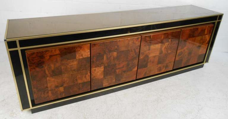 Large decorative four door credenza featuring patchwork burl wood doors, bronze mirrored top, and black mirrored sides with brass colored trim. Four fixed shelves provide ample storage space.