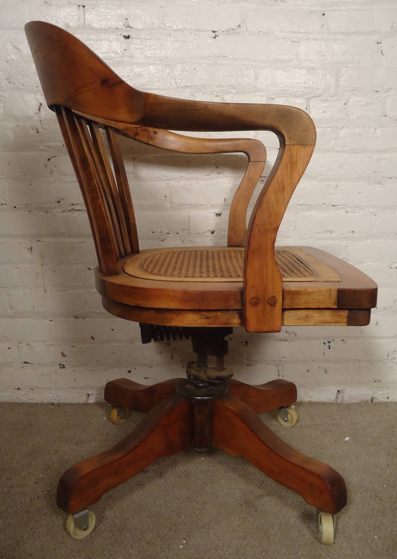 Intricately sculpted vintage-modern swivel desk chair, walnut with cane seat set on wheels. Very well made and newly refinished.
Manufactured by PAGE Business Furniture.

(Please confirm item location - NY or NJ - with dealer)