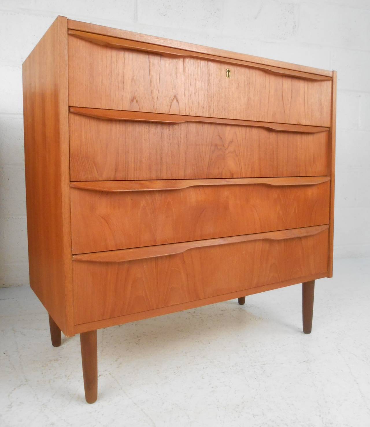 Matching pair of smaller scale four drawer teak dressers. Please confirm item location (NY or NJ) with dealer.