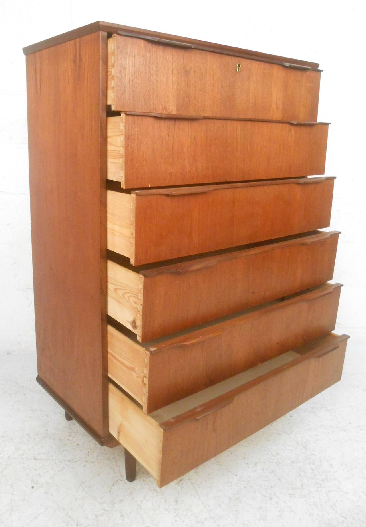 This vintage teak dresser makes a wonderful storage solution for any midcentury interior. This stylish case piece offers plenty of room for storage within its six hefty drawers. Carved drawer pulls and tapered legs add to it's charm, please confirm