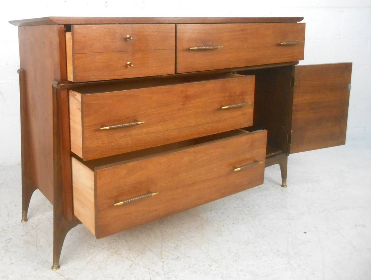 This mid-century credenza features a unique assortment of storage options, including McCobb style cane front cabinet. Unique drawer pulls and brass feet add to the vintage style of the piece. Please confirm item location (NY or NJ).