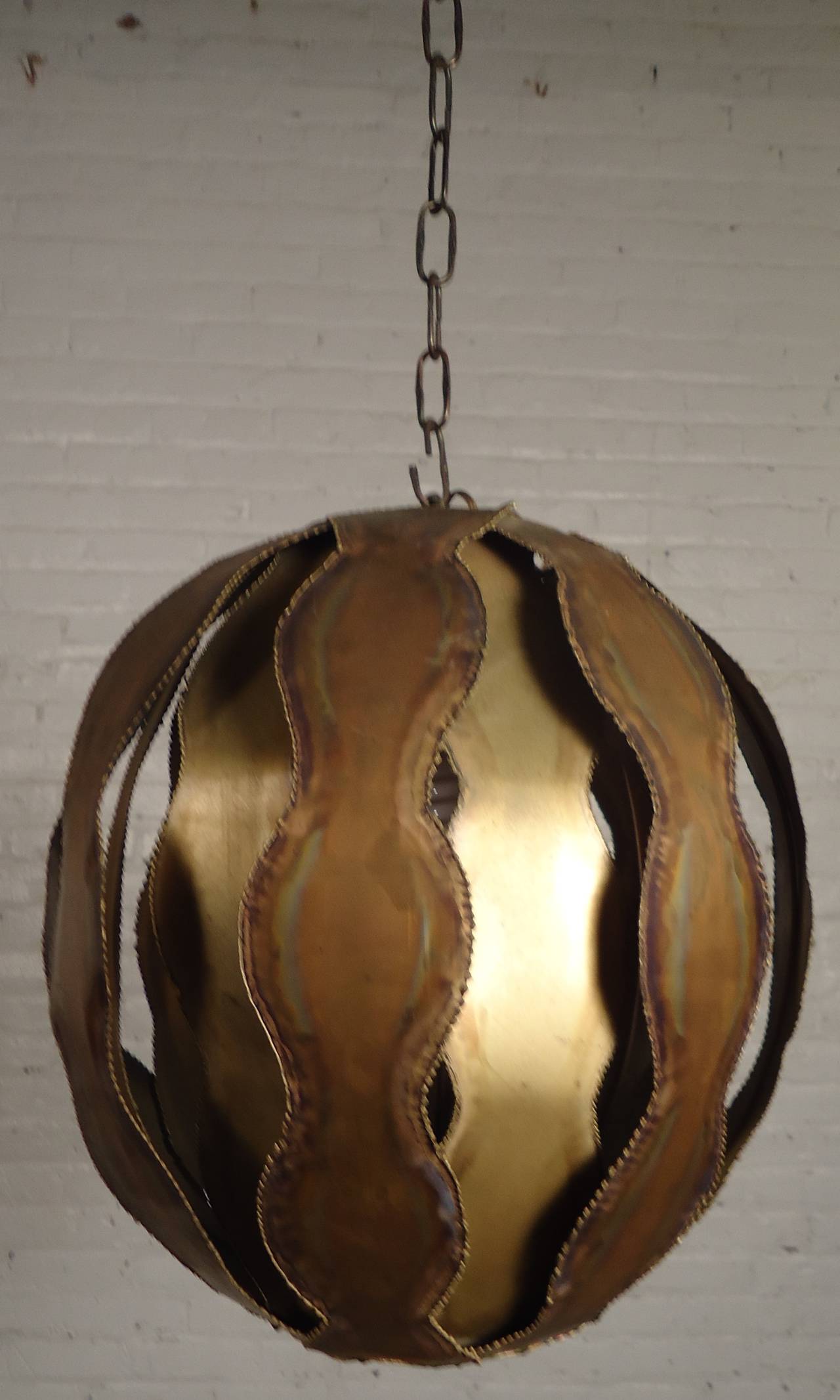 Vintage-Modern brass hanging globe-shaped pendant featuring one standard socket. Awesome torch cut metal with a handsome brutalist finish designed by Tom Greene.

(Please confirm item location - NY or NJ - with dealer)