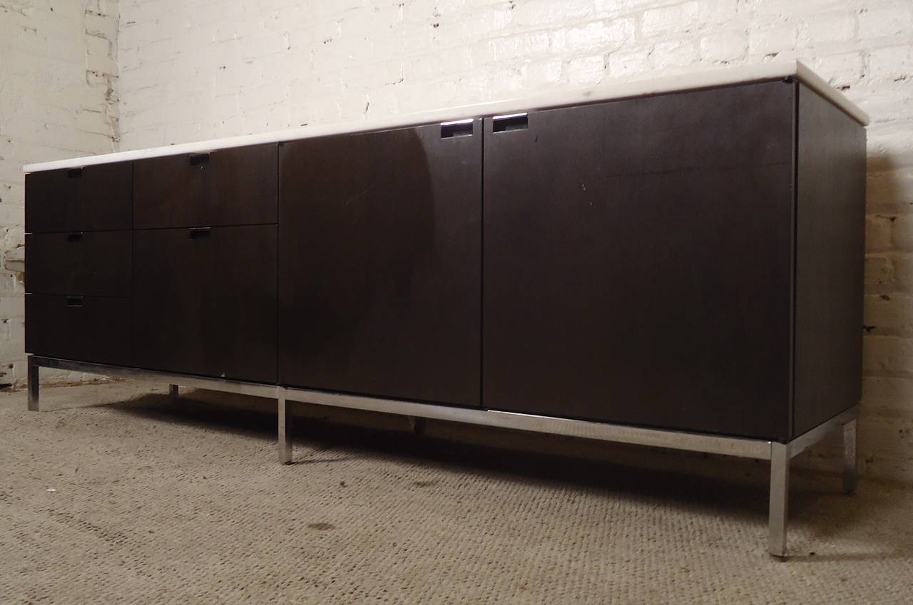 Attractive Mid-Century cabinet by Knoll with white marble top. Dark teak wood with accenting polished chrome base and handles. Five drawers and two-door cabinet, with adjustable shelves (two additional shelves available).

(Please confirm item