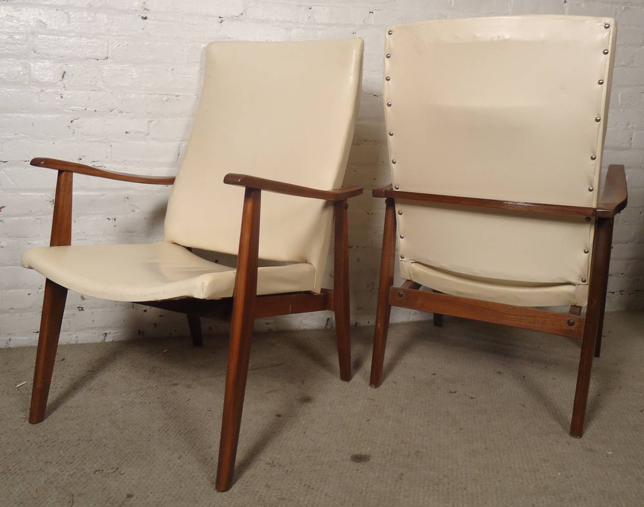 Vintage-Modern pair of Danish arm chairs, each featuring upholstered back and seat with beautifully sculpted teak legs and arm rests.

(Please confirm item location - NY or NJ - with dealer)