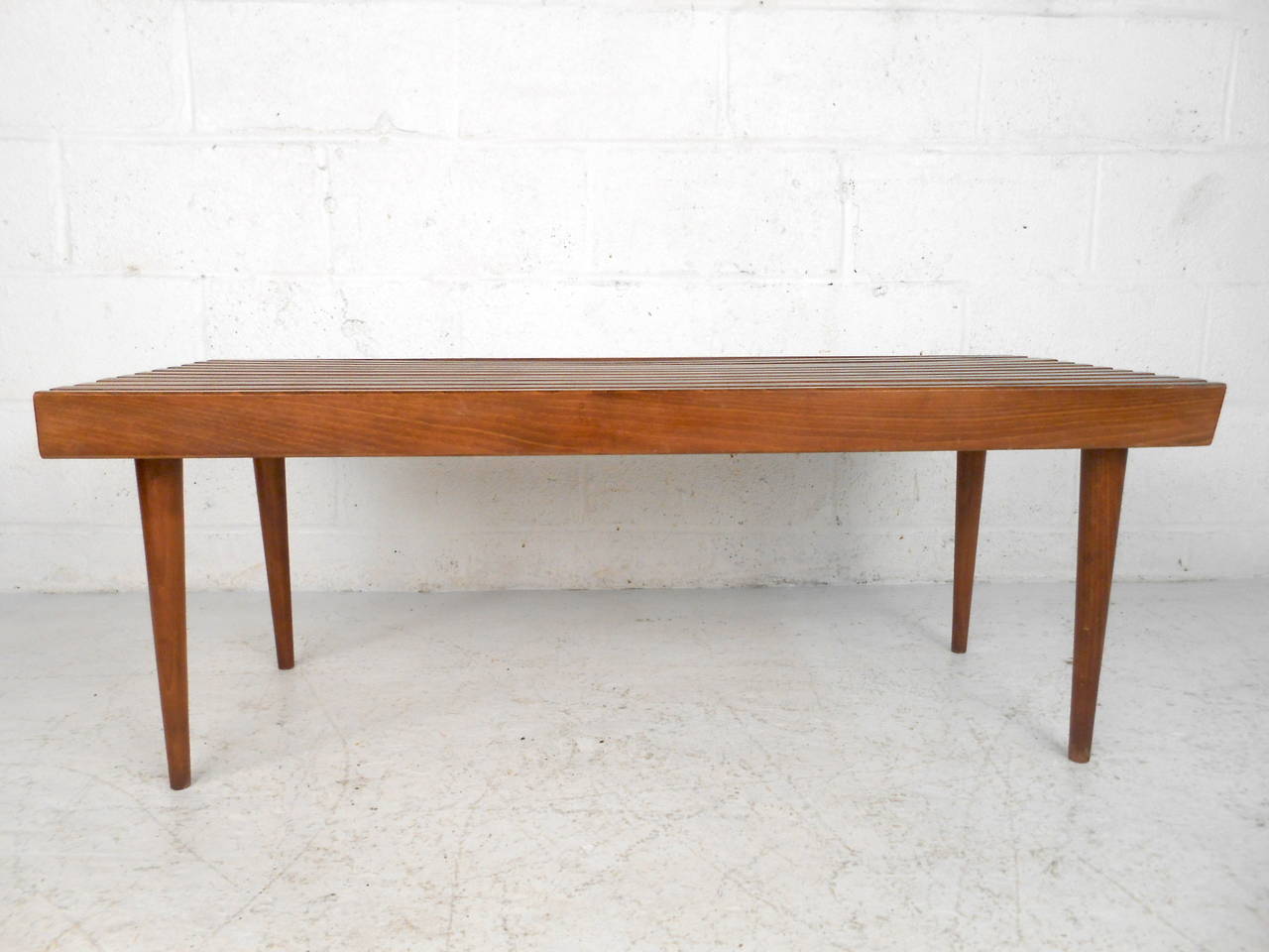 This mid century slat bench in the style of George Nelson features a solid walnut construction with removable tapered legs which offers a distinct modern flare to any home or office space. 

Please confirm item location (NY or NJ) with dealer.