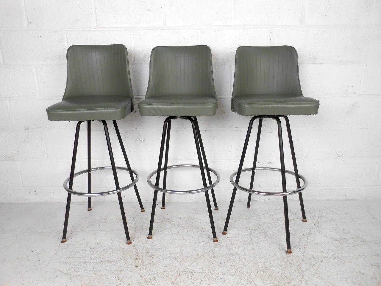 This set of three mid century bar stools by Atlas Specialty Manufacturing feature a green vinyl upholstery, swivel base, and chrome foot rest.

Please confirm item location (NY or NJ) with the dealer.
