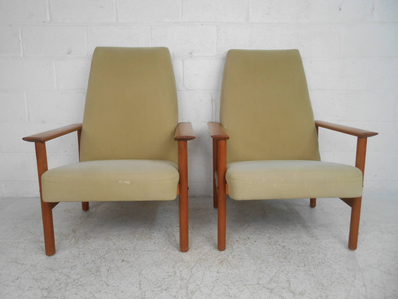 This matching pair of Mid-Century lounge chairs offers comfortable high back seating for any interior teak frames and unique angled backs make these a stylish and comfy addition to any home. Please confirm item location (NY or NJ.)