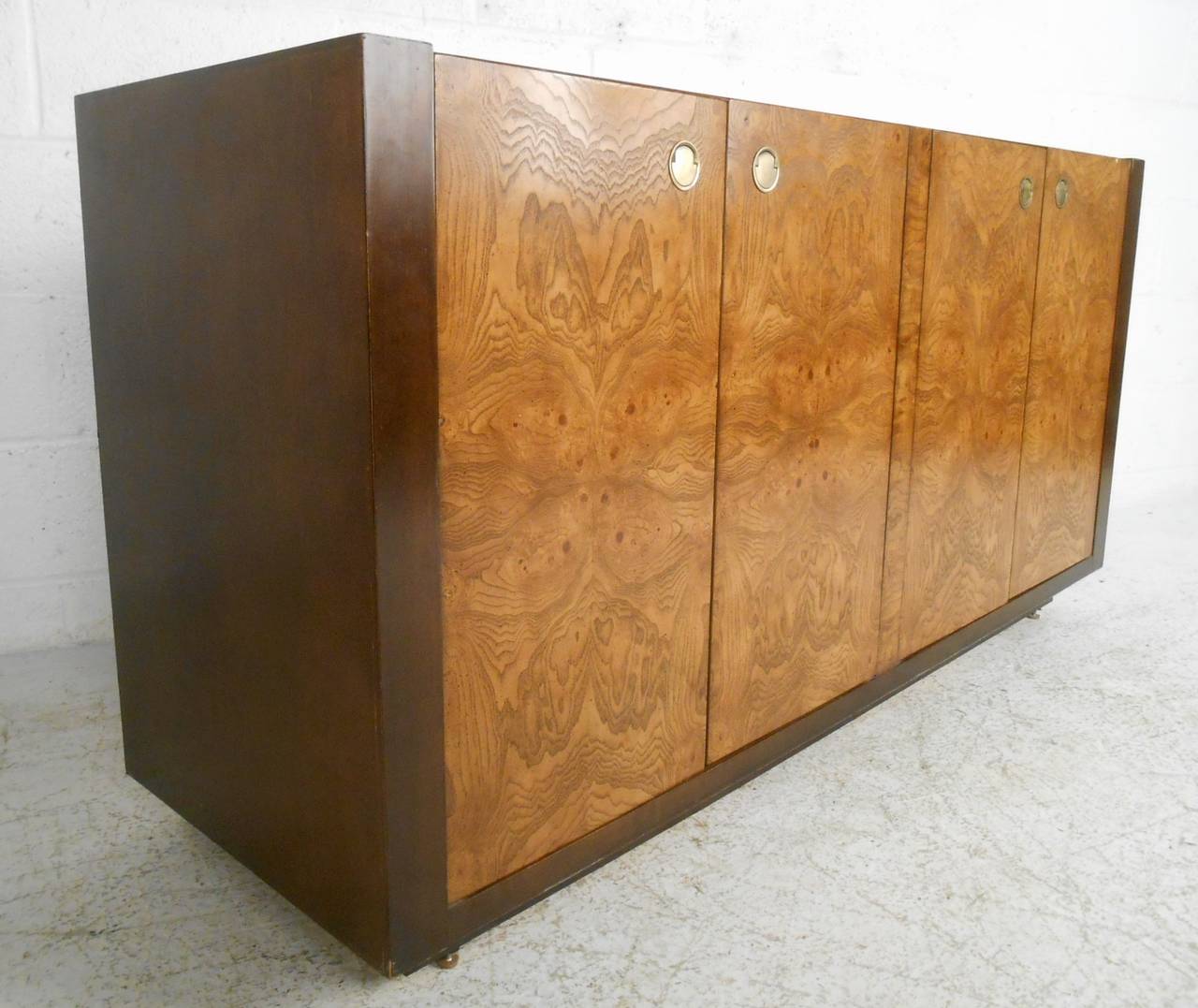 This exquisite burlwood credenza by Century Furniture offers dual cabinets with interior drawers for plenty of space for serving or storage. Unique brass trim pulls and two tone construction make this a wonderful addition to any interior.  Please