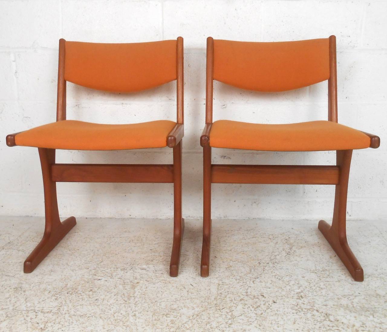 This midcentury set of teak dining chairs are comfortably designed and feature stabilizing stretchers along with unique frames. Please confirm item location (NY or NJ).