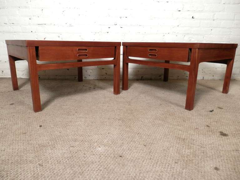 Mid-Century Modern designed nightstands made of teak grain. Each with a shallow drawer for storage, broad tops and carved inset handles.

(Please confirm item location - NY or NJ - with dealer).