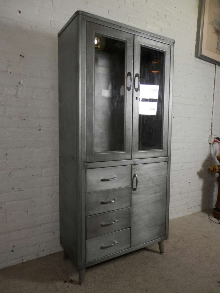 Factory era storage cabinet with large glass front doors that trigger an inside light when opening and closing. Four additional drawers and bottom cabinet for extra storage. Restored in an industrial style metal finish.
Perfect for living room,