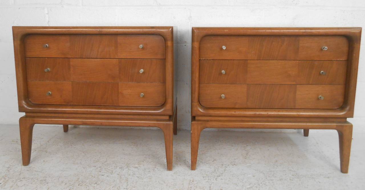 Pair of two-drawer midcentury nightstands offer stylish vintage storage to bedroom or living room. Tapered legs, midcentury drawer pulls, and rich walnut finish add to the appeal. Please confirm item location (NY or NJ) with dealer.