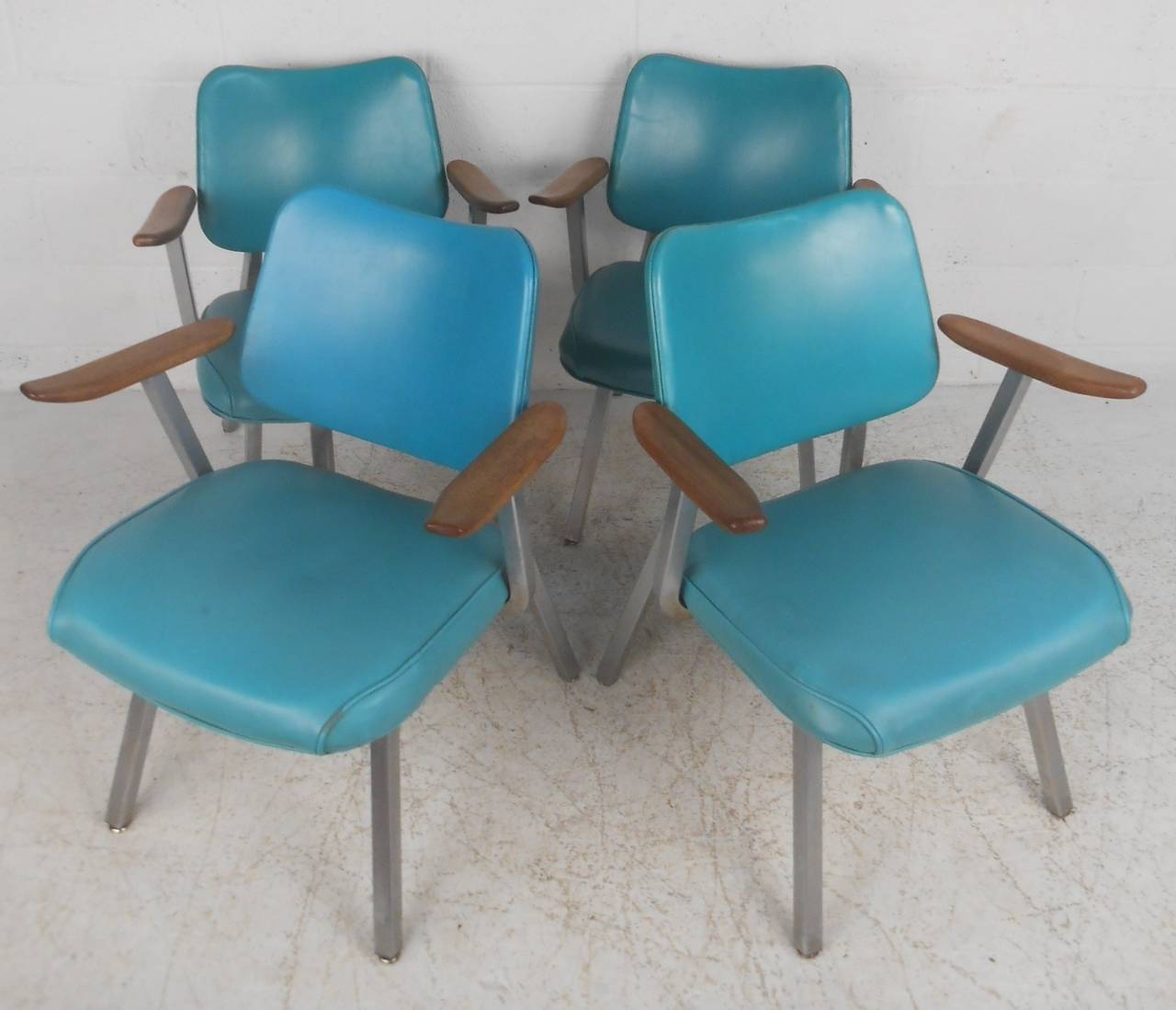 Set of four Royal metal chairs with vinyl upholstery, metal frames, and walnut armrests. Please confirm item location (NY or NJ) with dealer.