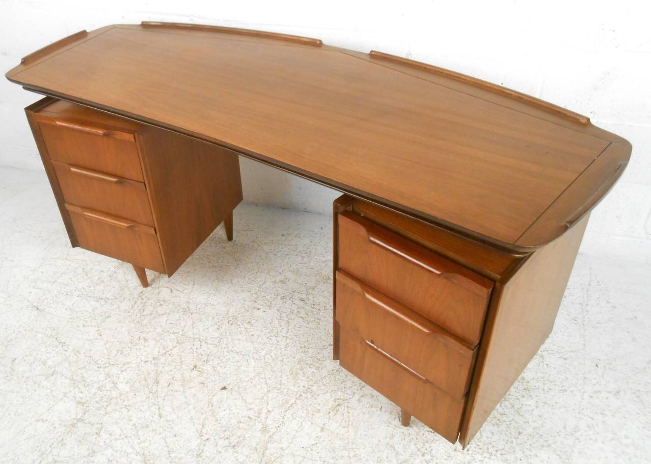 This unique mid-century desk features turned edge floating top, five drawers for storage, and a finished back. Tapered legs and unique danish style construction make this walnut piece a wonderful addition to any home or office. Please confirm item