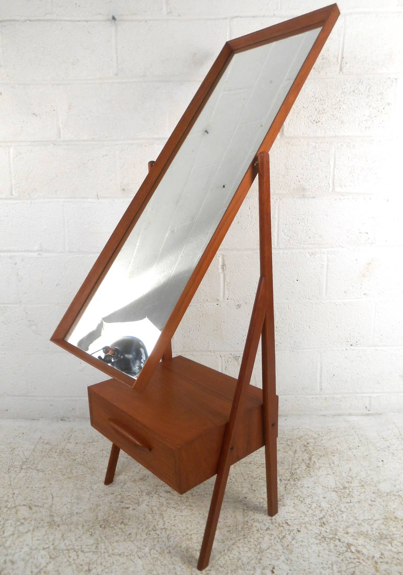 This wonderful Danish made teak dressing mirror features a single drawer for storage and a tilting swivel mirror. Elegant in it's minimal design, this unit will easily compliment both a residential or retail application.  Please confirm item