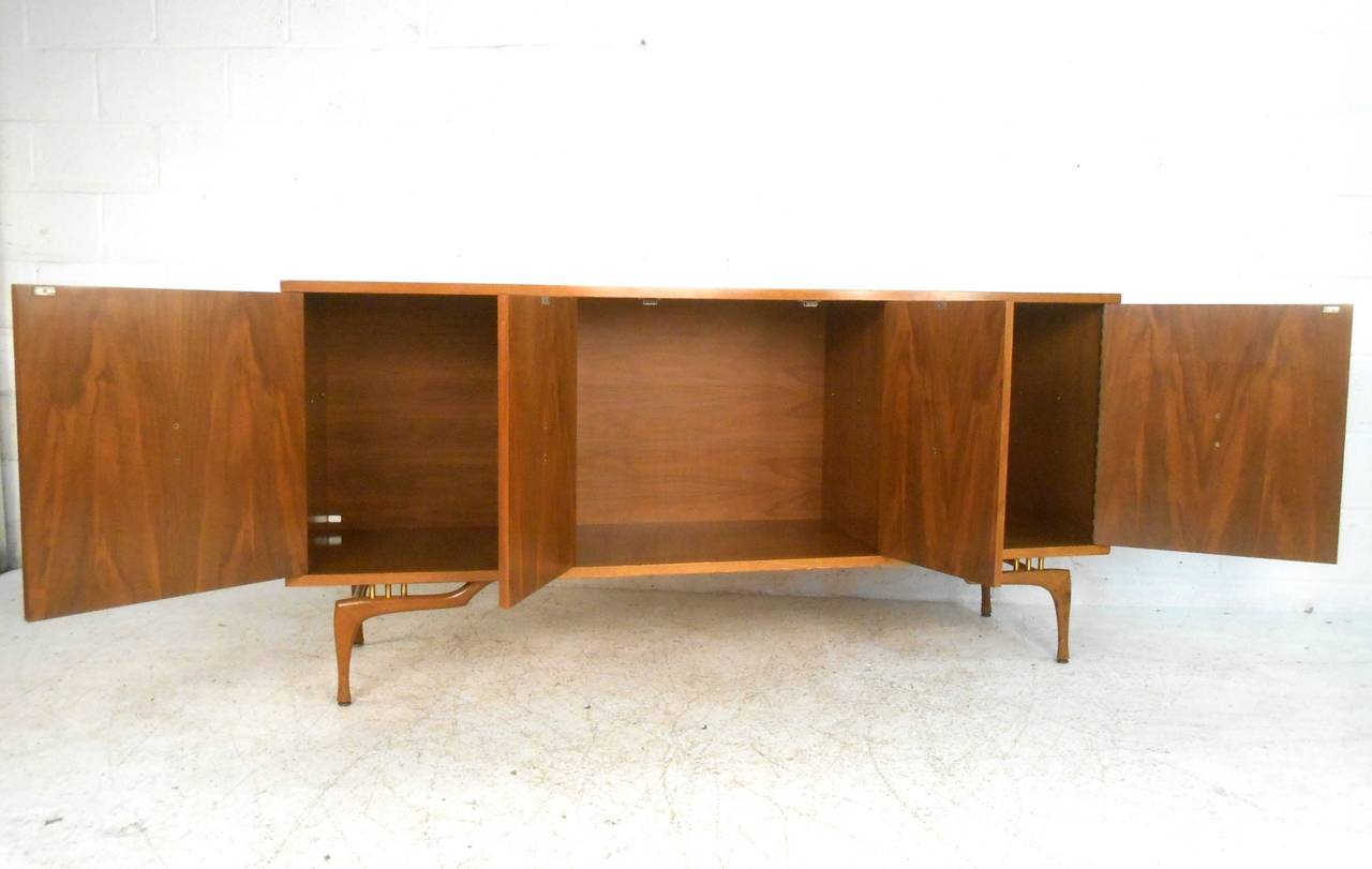 Spacious cabinet style storage makes organization easy, while the unique legs with brass trim and shapely cabinet pulls on this midcentury sideboard makes it a wonderful addition to any home or business. Please confirm item location (NY or NJ).