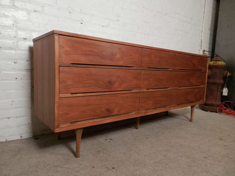Sometimes you don't need a lot of flash to be elegant. This nine drawer dresser has function and style. Beautiful walnut grain throughout, clean lines, delicately shaped legs and inset handles help give this a sleek modern look.

(Please confirm