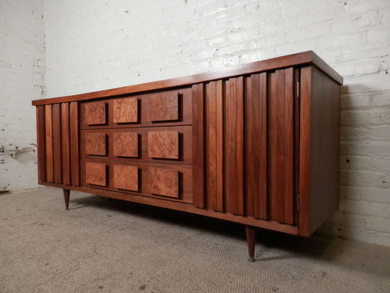 Vintage modern long dresser by United with wonderful burl walnut accents that double as handles. Features sculpted side doors, tapered legs and slightly curved front. Very unusual, but attractive design.

(Please confirm item location - NY or NJ -