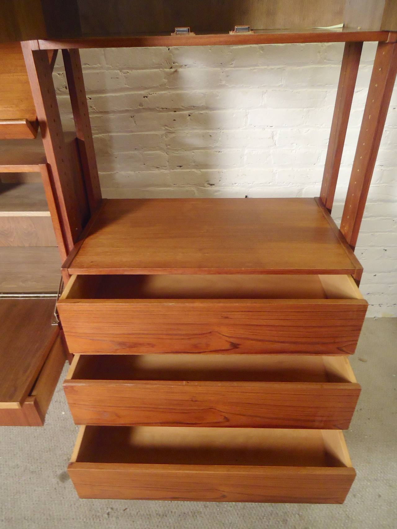 Tall teak grain bookcase unit with multiple cabinets, fully adjustable. Drop front desk, book shelves, two door cabinets, drop front cabinet, dresser drawers, slanted shelf. This piece has the works, with a finished back in addition!

Pictures