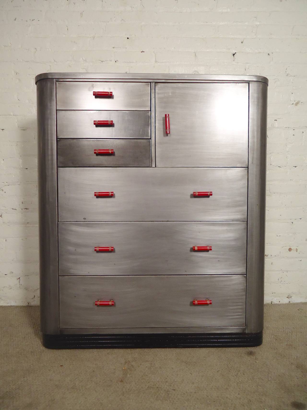 Fantastic metal dresser designed by Norman Bel Geddes featuring three wide drawers, three small and side cabinet. Original bright red pulls. Refinished in a bare metal style finish.

(Please confirm item location - NY or NJ - with dealer).