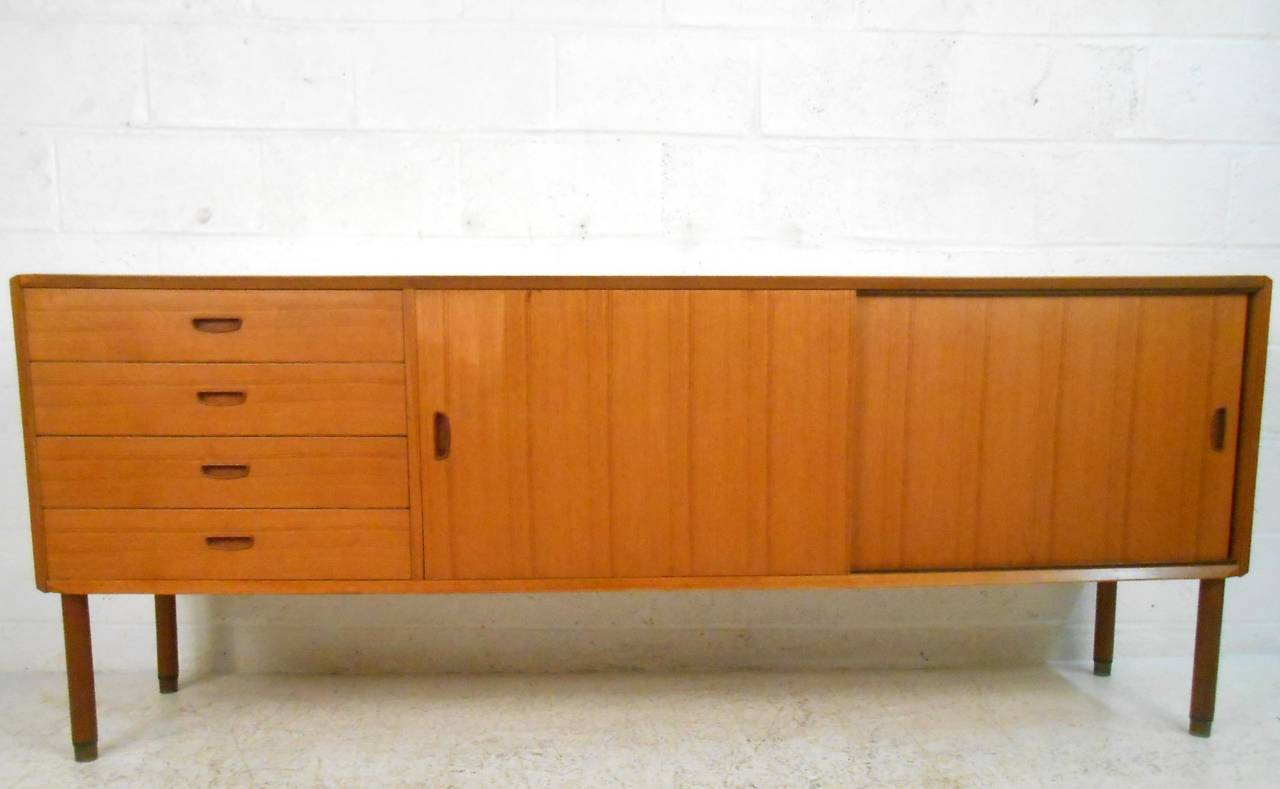 This unique server features squared off legs with brass tips, midcentury carved drawer or cabinet pulls, and plenty of storage space for a variety of uses. Ideal for table service or office storage, please confirm item location (NY or NJ).