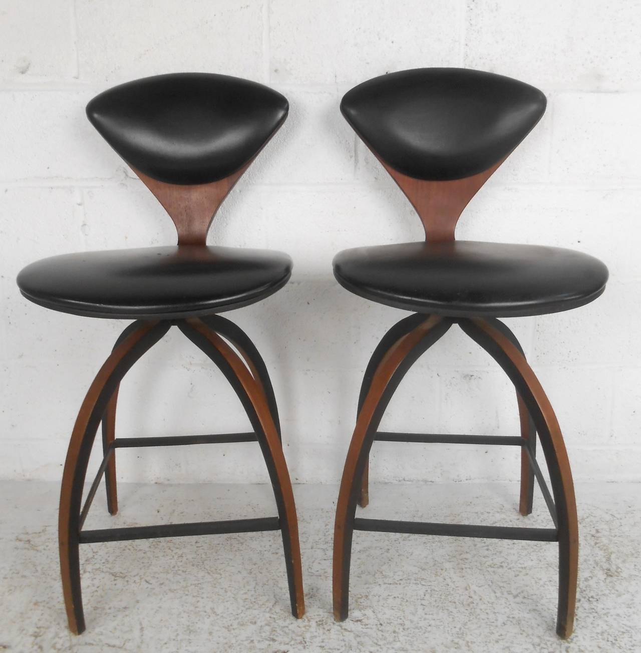 This pair of vintage barstools by Norman Cherner feature unique bentwood construction, vinyl upholstery, swivel base, and the original manufacturer's label. Dated from 1966, these classic stools will make a wonderful addition to bar or counter.