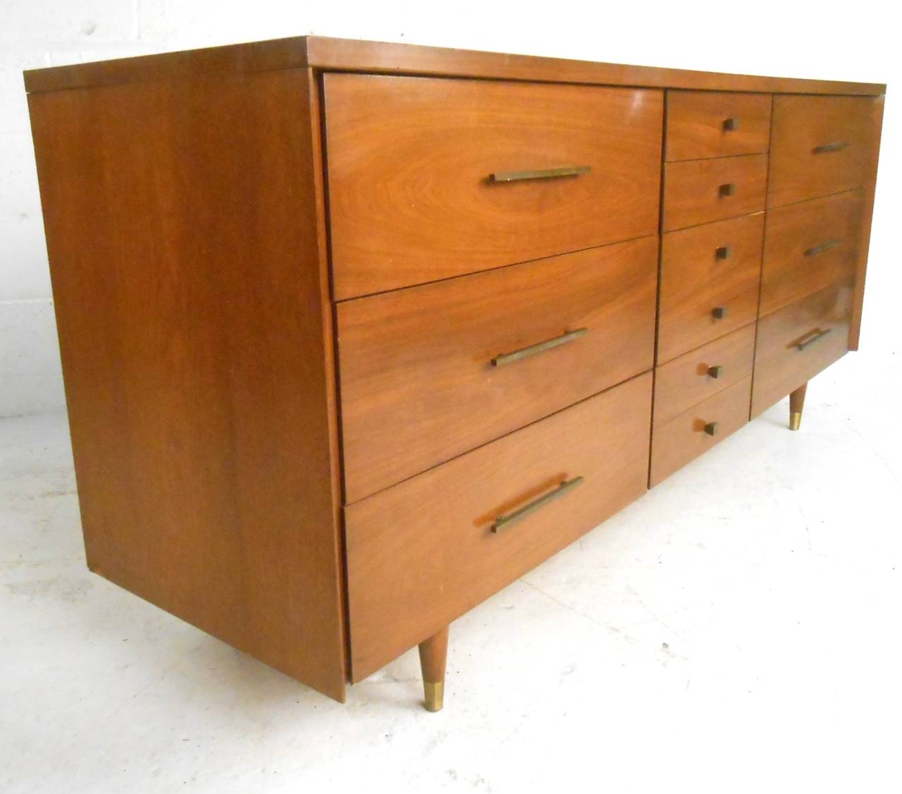 This wonderful vintage dresser features charming brass pulls, tapered legs, and quality Mid-Century construction. Original John Stuart badge still affixed, this lovely piece is the perfect combination of style and storage for any interior. Please