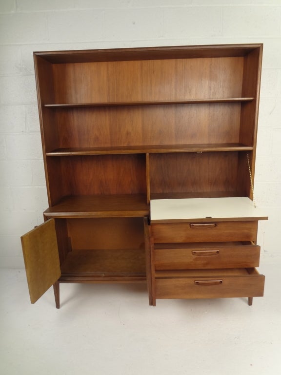 Mid-century walnut cabinet with recessed pulls, open shelves, and storage/drawers below.