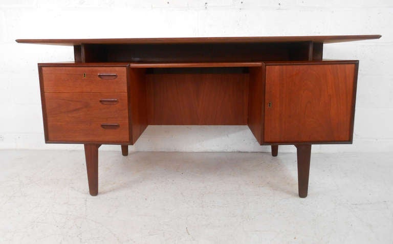 This gorgeous Danish Teak desk features classic mid-century floating top design, and plenty of storage space. Fantastically designed this stunning workspace has a finished back, complete with auxilliary storage or display, makes the perfect addition