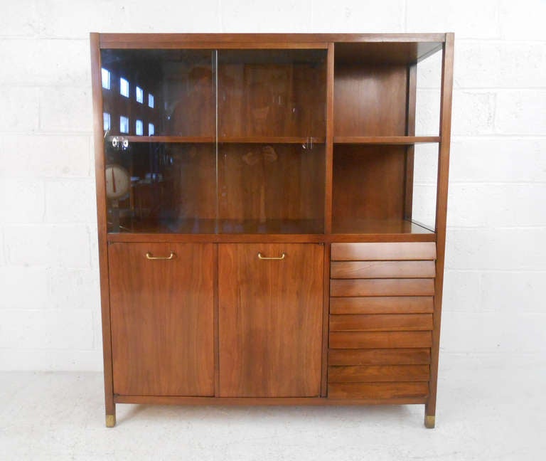 This unique mid-century walnut display cabinet features American of Martinsville's classic louvered drawer fronts, beautiful brass cabinet pulls, and sliding glass windows. Please confirm item location (NY or NJ).