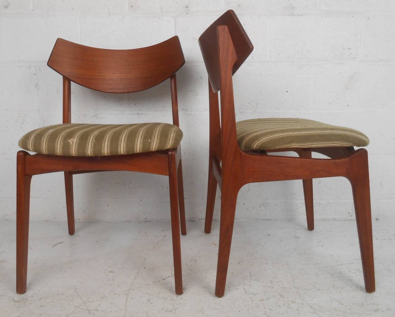 Set of four mid-century modern teak dining chairs with bent-ply backrests and solid teak frames. The sculpted back rests, thick padded seats, and bowtie shaped stretchers provide sturdiness and maximum comfort in any seating arrangement. Please