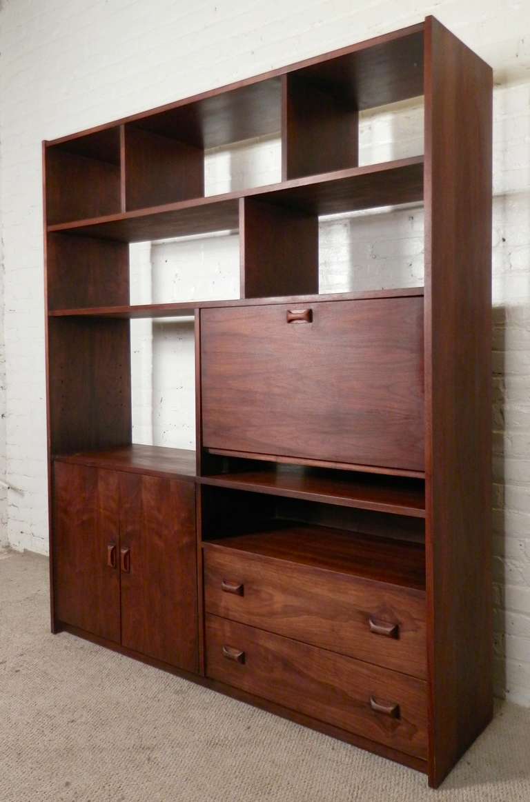 Large mid-century standing wall unit made with rich walnut grain, sculpted Danish style handles and enough storage compartments for all your living room items. 
Features multi-size cubbies, two door cabinet with adjustable shelf, two wide drawers