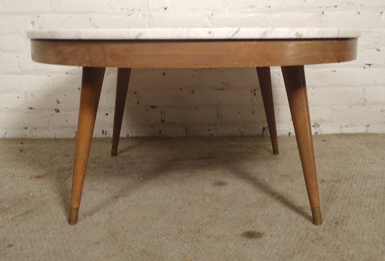 Round cocktail table with thick marble top. McCobb style tapered legs with brass feet. 

(Please confirm item location - NY or NJ - with dealer)