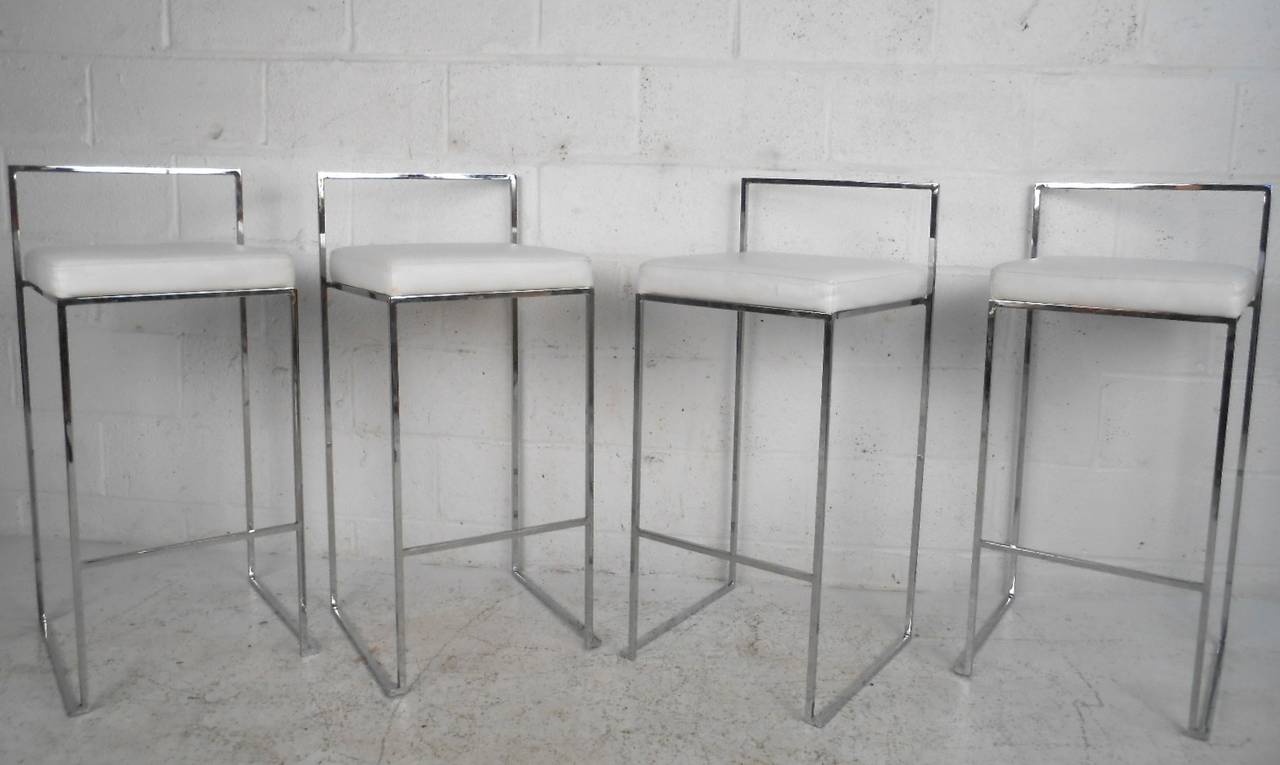 This beautiful set of four Milo Baughman style stools features heavy chrome frames covered with white leather. Simple modern style adds to the comfort these low back stools provide, making them a great addition to any interior. Please confirm item