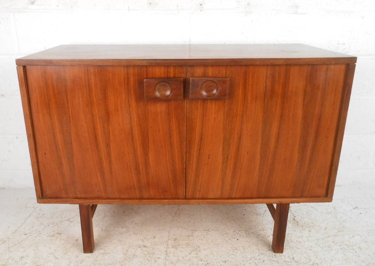This unique vintage cabinet showcases lovely rosewood veneer along with uniquely carved door pulls. Sturdy construction and shelves for storage make this a stylish option for use as a tv console, printer table, or a variety of needs. Please confirm