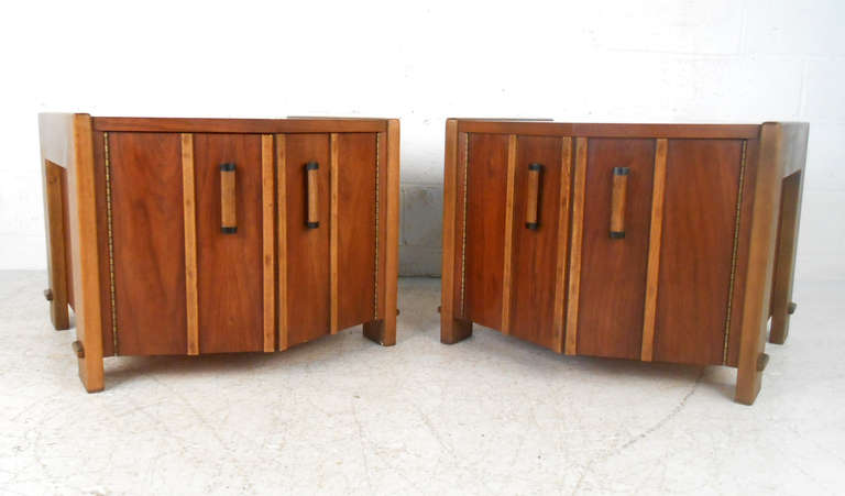 This uniquely designed and well-made pair of end tables features fantastic lines and wood choice, as well as sculpted legs. With plenty of functional storage and finished backs this Mid-Century set is perfect for bedroom, living room, or waiting