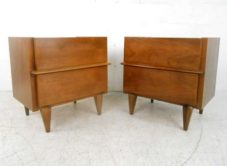 These beautiful walnut nightstands by American of Martinsville features the sturdy construction and fantastic wood grain the mid-century manufacturer is so well known for. Withe tapered legs and unique drawer pulls this set make a stylish addition