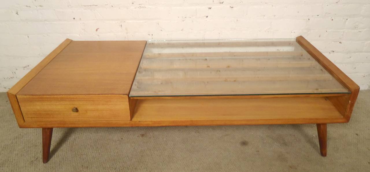 Mid-Century Modern cocktail table with large glass top. Blonde color wood grain and tapered cone legs in the style of Paul McCobb, with single drawer. Lots of open storage space.

(Please confirm item location - NY or NJ - with dealer).