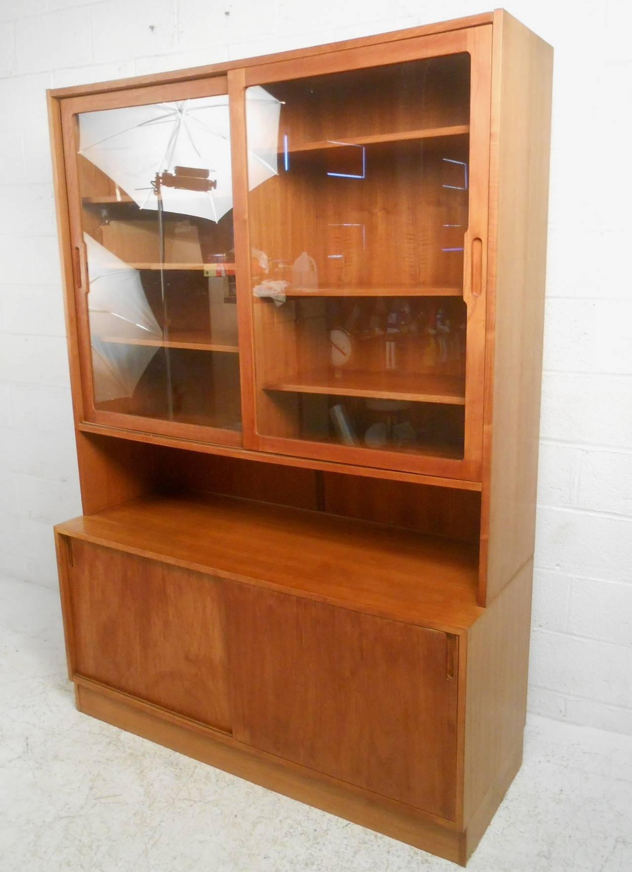 This beautiful Danish Teak cabinet makes a stylish storage option for any room. Spacious glass curio sits atop sliding cabinets, offering a nice variety of organizational space. Unique midcentury style and sturdy Danish construction makes this a