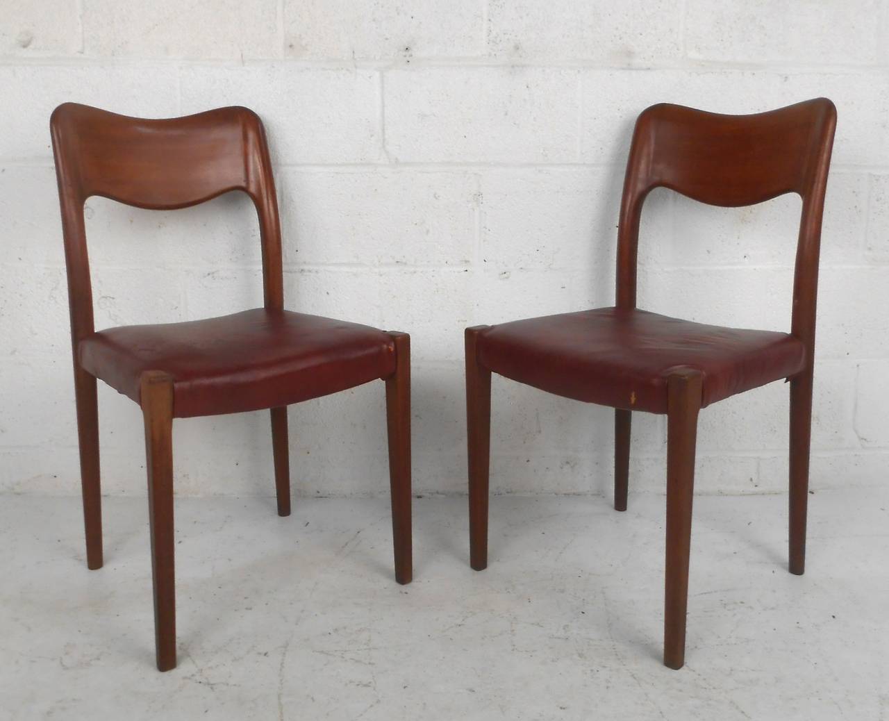 This set of six beautiful leather and rosewood dining chairs includes two armchairs in the tremendous style and design of Niels Otto Møller. Sculpted seat backs and a wonderful rosewood finish set this set apart from other Midcentury seating