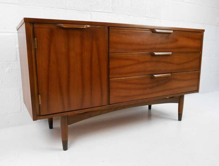 This stylish vintage storage cabinet features it's original walnut finish and offers a combination of shelf and drawer storage perfect for any setting. Smaller scale midcentury credenza is perfect for use as a television or office cabinet. Please