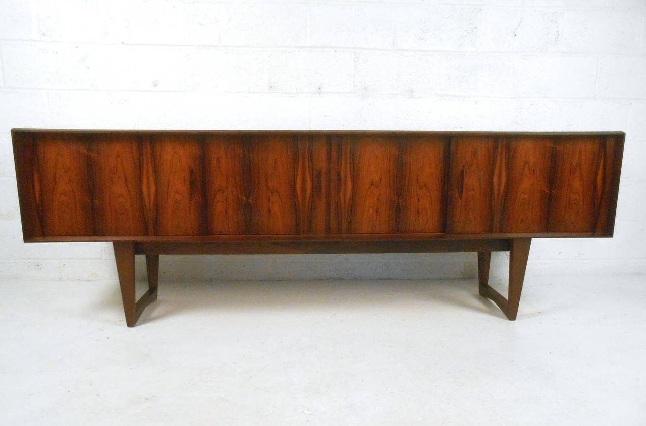 This gorgeous vintage Rosewood sideboard packs plenty of space for storage into a petite frame with quality construction. Center drawers and two spacious shelved cabinets make this a stylish and functional addition to any room, while unique sled