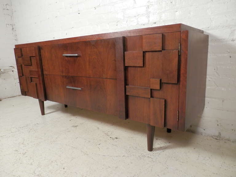 Mid-century modern walnut credenza with brutalist style relief. Left side cabinet, right side record cabinet, two large drawers in the middle. Nice tapered legs.

(Please confirm item location - NY or NJ - with dealer)