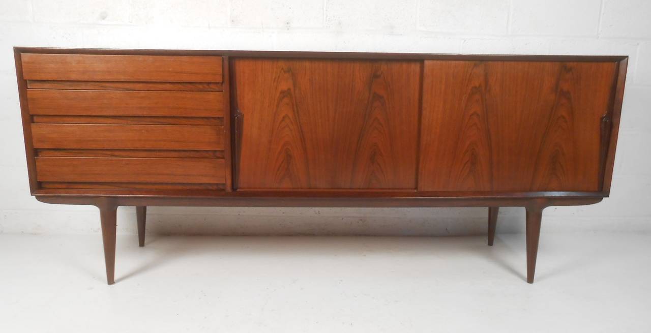 Designed by Gunni Omann and produced by Omann Jun, Model 18, rosewood credenza. Four drawers and two sliding doors with adjustable shelf. Please confirm item location (NY or NJ) with dealer.