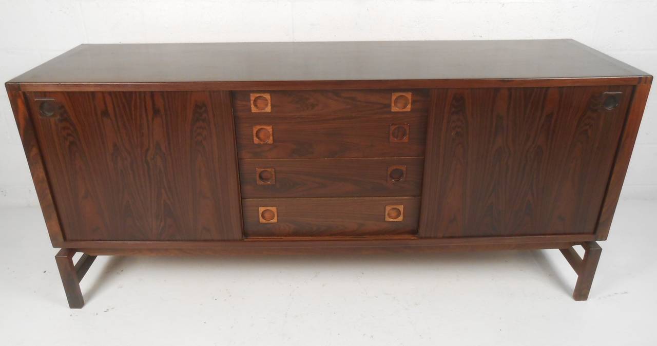 Quality Scandinavian rosewood sideboard boasts a rich vintage wood finish, unique carved drawer pulls, and spacious interior shelf space. including four drawers and two storage cabinets. Mid-Century modern Danish modern credenza by H.P. Hansen's