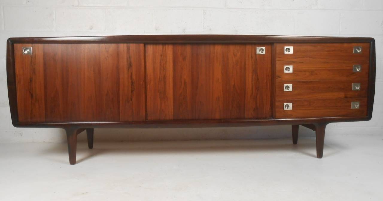 Exceptionally well-crafted rosewood sideboard by H P Hansen of Denmark features stylish Scandinavian Modern design. Four drawers and two sliding doors with recessed stainless pulls, a raised edge on the front and beautifully matched deep rosewood