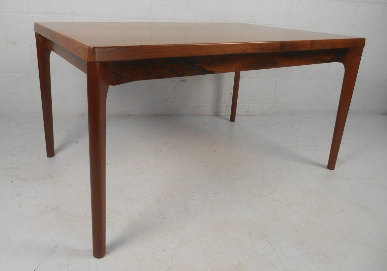 Scandinavian Modern dining table and six chairs in rosewood as designed by Danish icon Johannes Andersen. Please confirm item location (NY or NJ) with dealer.