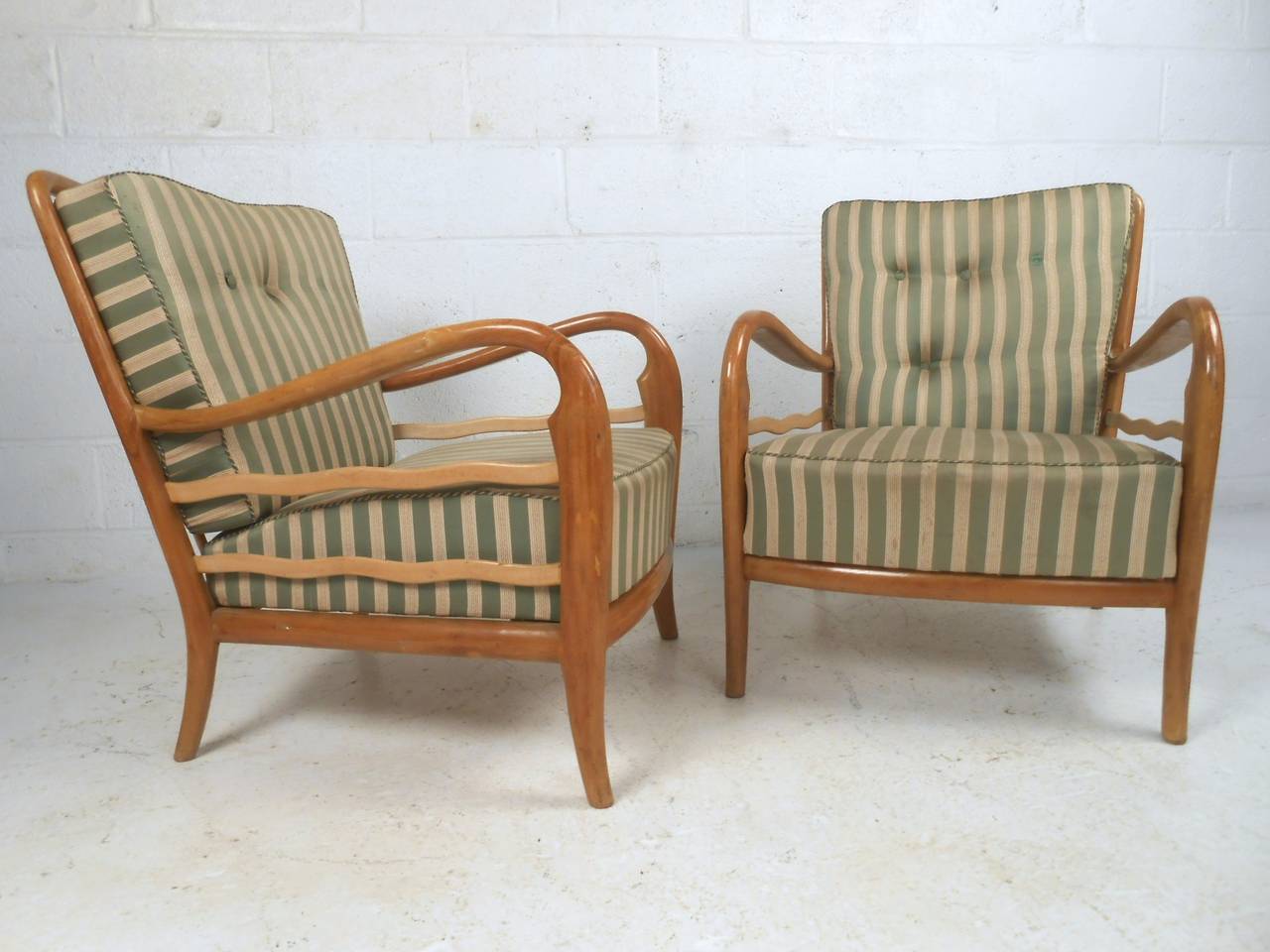 This pair of sculpted armchairs features vintage style, uniquely shaped armrests and backs, and comfortable vintage upholstery. Spoked back and stylish design make this matching midcentury pair the perfect addition to any interior. Please confirm