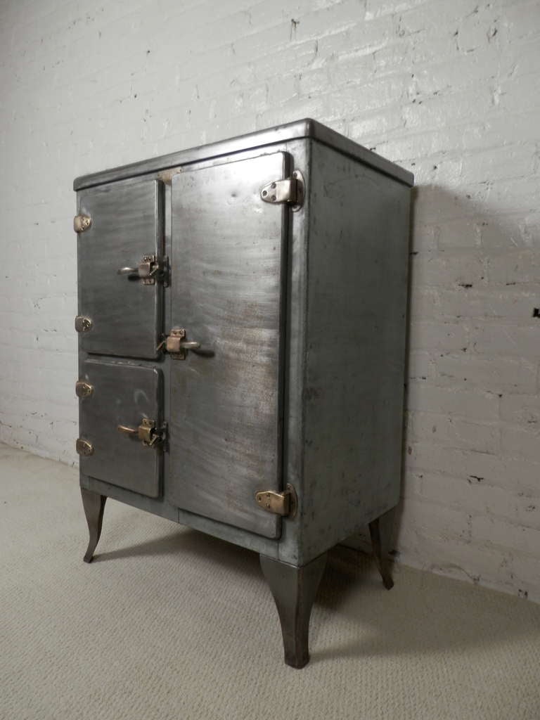 Industrial metal ice box from the early 1900s. Has been stripped to bare metal and lacquered. Features brass hardware and latches. 